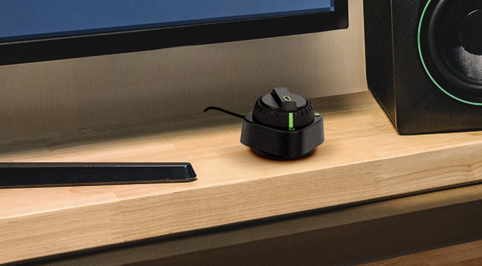 Mando de control de escritorio CRDV incluido con el Mackie CR8SBT, sobre una mesa junto a un monitor de estudio