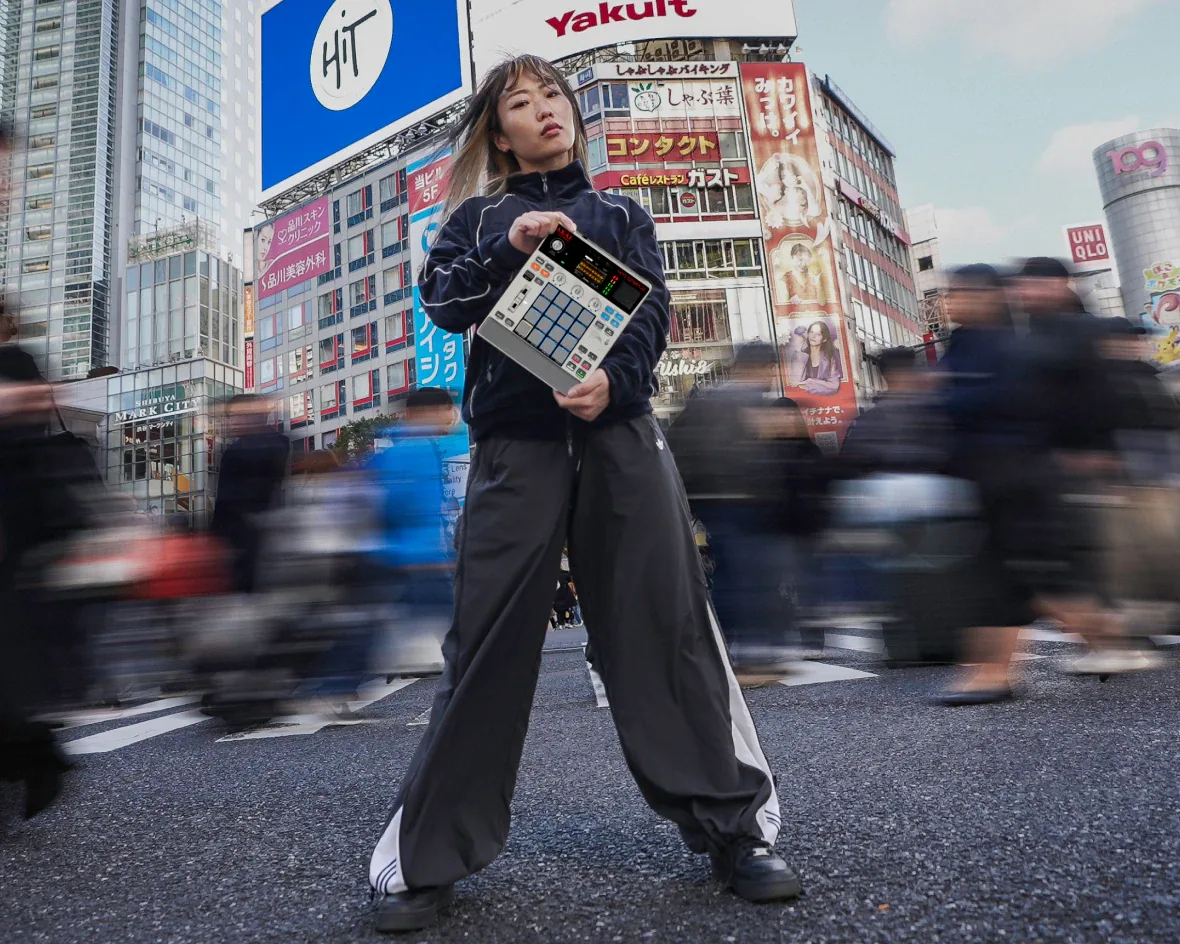 Productora sosteniendo la Akai MPC Sample en el cruce de Shibuya, Tokio