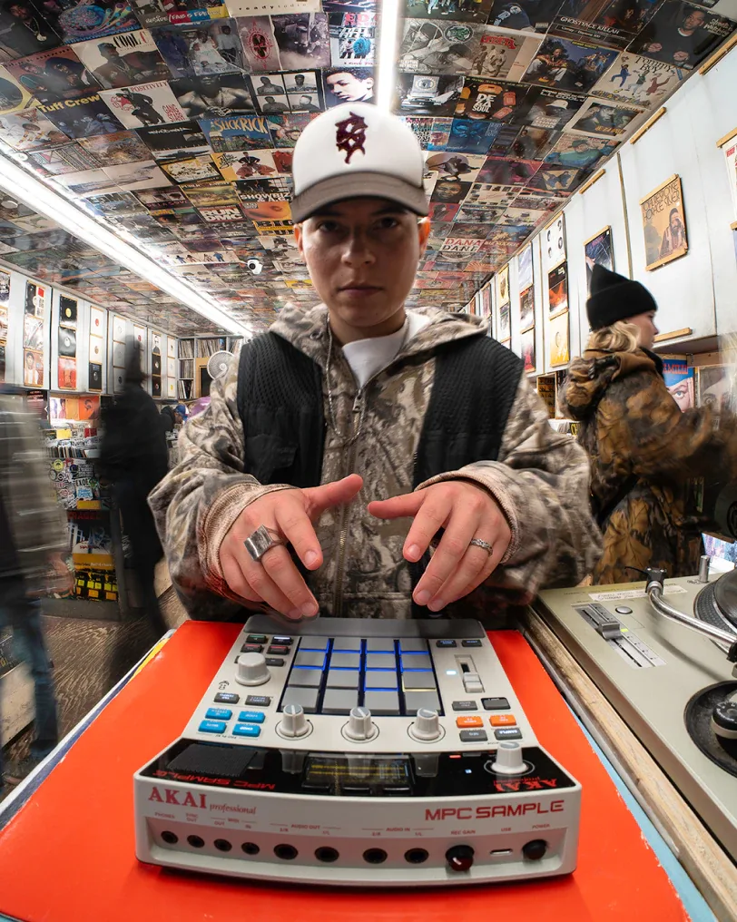 Beatmaker usando la MPC Sample en una tienda de discos junto a un plato giradiscos