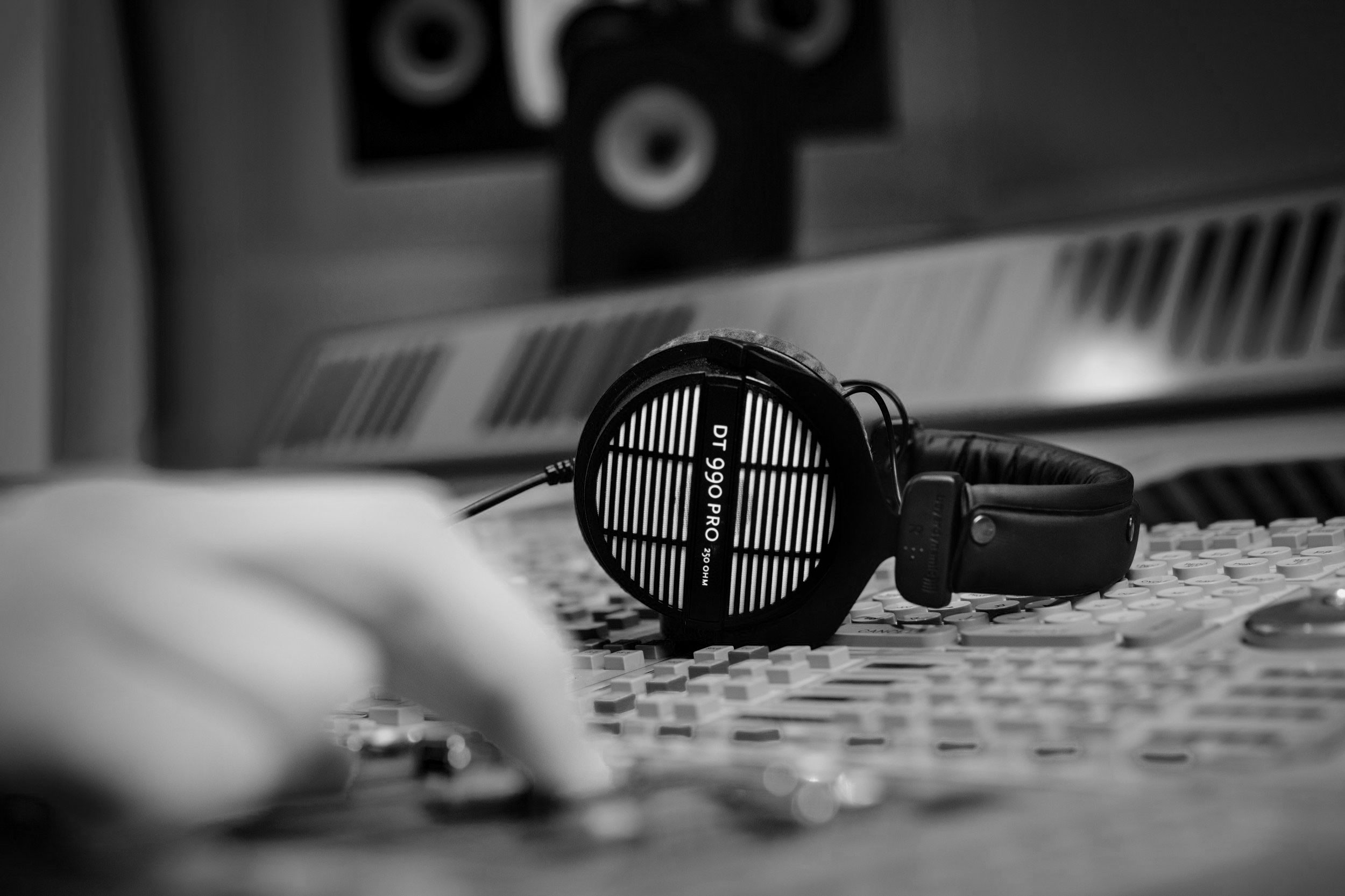 Auscultadores Beyerdynamic DT 990 PRO sobre uma mesa de mistura enquanto um técnico ajusta os controlos