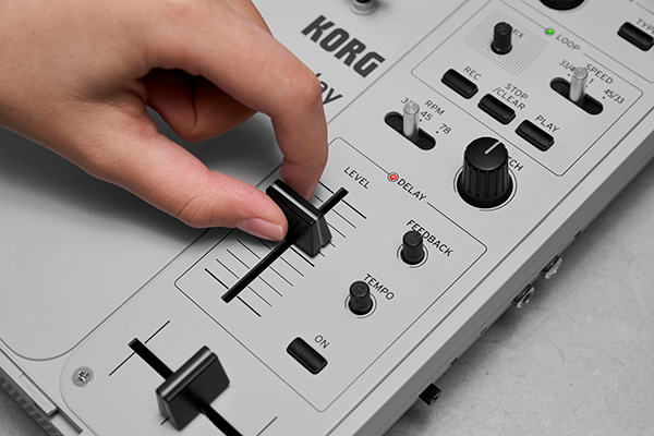 Dedo a mover um fader no painel de controlo do Korg handytraxx play, junto aos controlos de delay