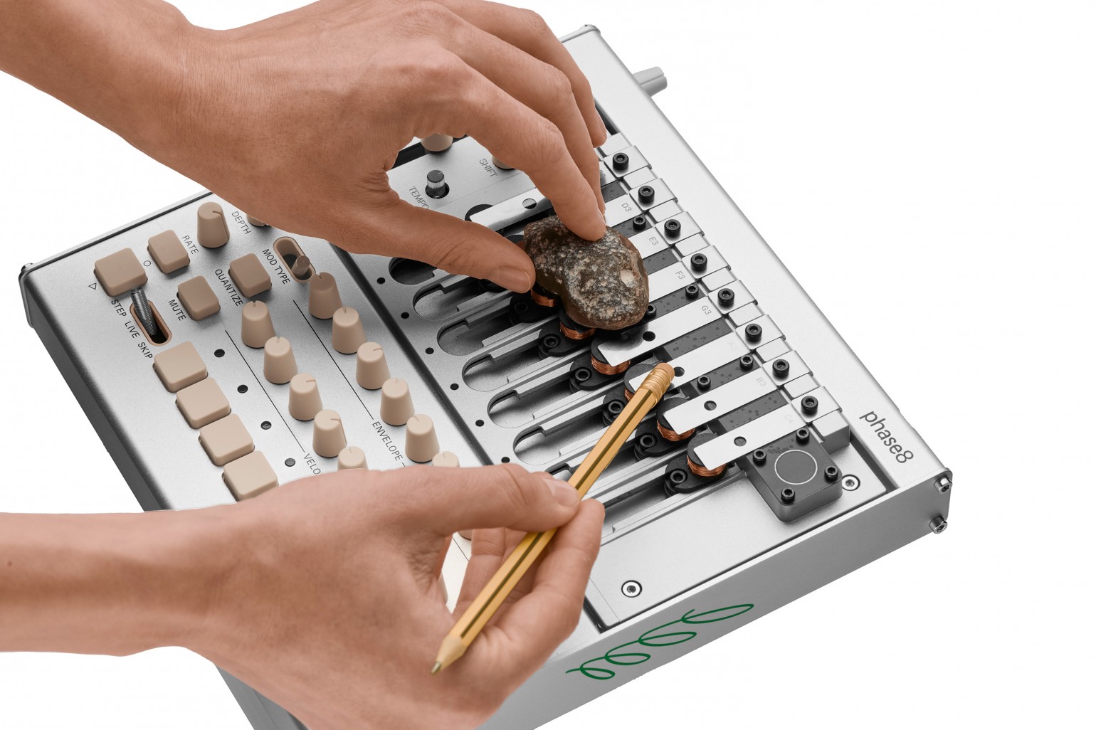 Manos tocando el Korg phase8 con una moneda y una varilla apoyadas sobre los resonadores