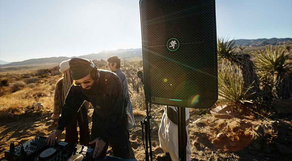 Controladora de DJ conectada a un Mackie Thump GO sobre trípode en una sesión al aire libre