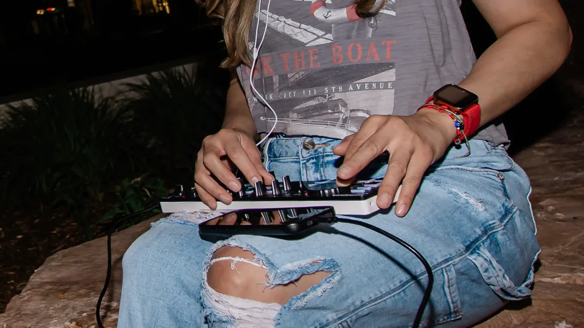 DJ pinchando con la Numark MixTrack Go apoyada sobre las rodillas al aire libre